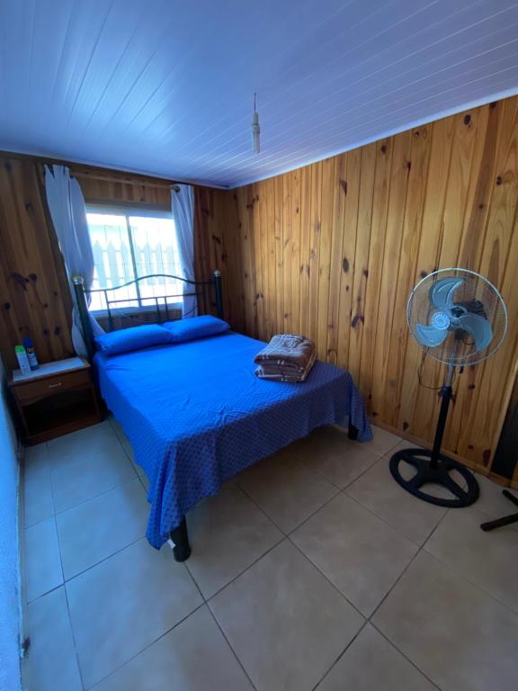 a bedroom with a blue bed and a fan at Hermosa cabaña totalmente equipada en barra del Chuy in Barra del Chuy