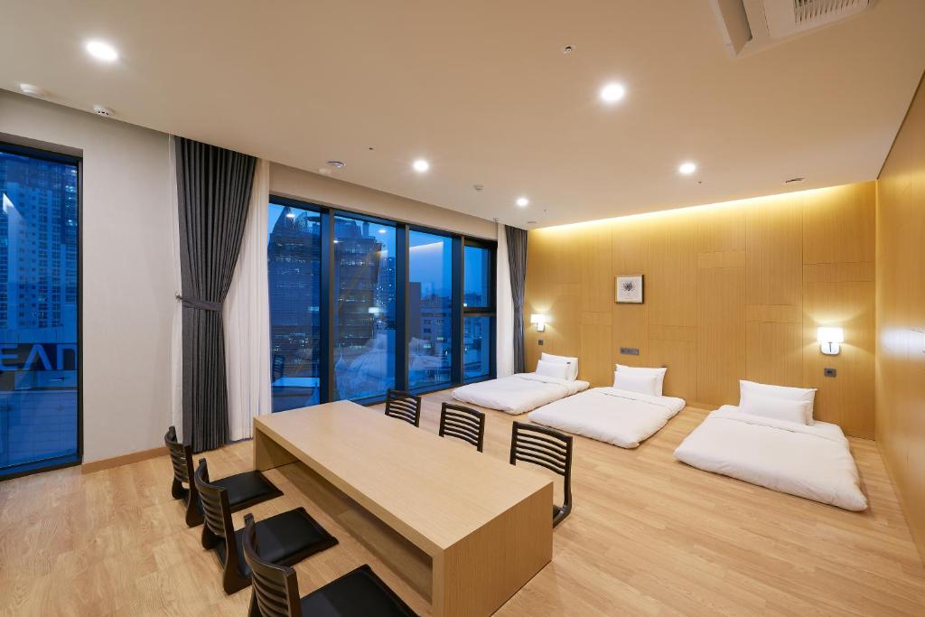 a room with two beds and a table and chairs at CS Hotel in Gwangju