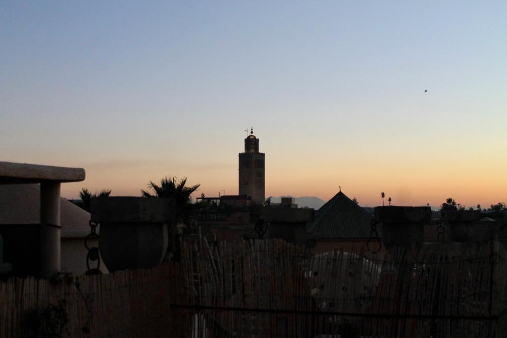 una silueta de un edificio con una torre de reloj al atardecer en Hostel kif kif annex en Marrakech