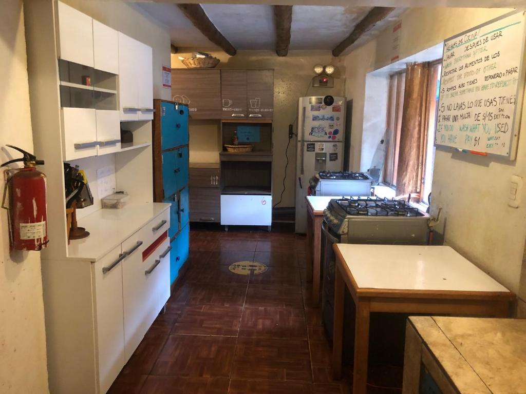 a kitchen with white appliances and a table in a room at Intihuatana Hostel in Pisac