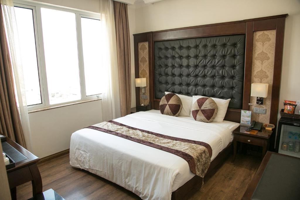 a bedroom with a large bed and two windows at CityBay Palace Hạ Long Hotel in Ha Long