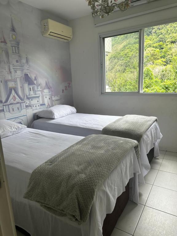 two beds in a room with a window at Rio Centro Barra da Tijuca in Rio de Janeiro