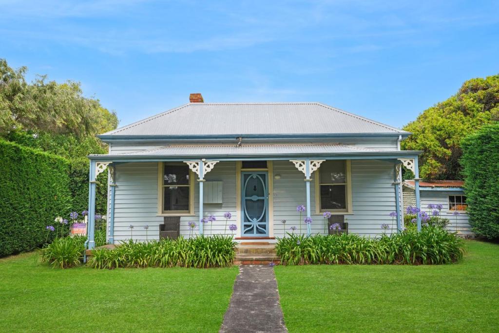 a blue house with a lawn in front of it at Palm Cottage in Port Fairy