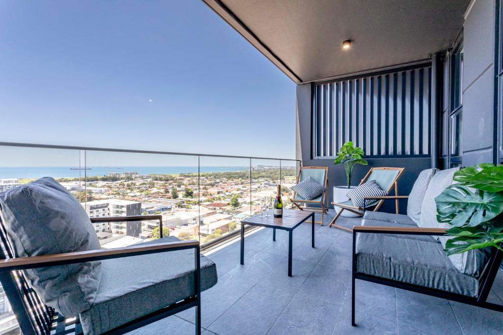 a balcony with chairs and tables and a view of the city at Kula Wollongong in Wollongong