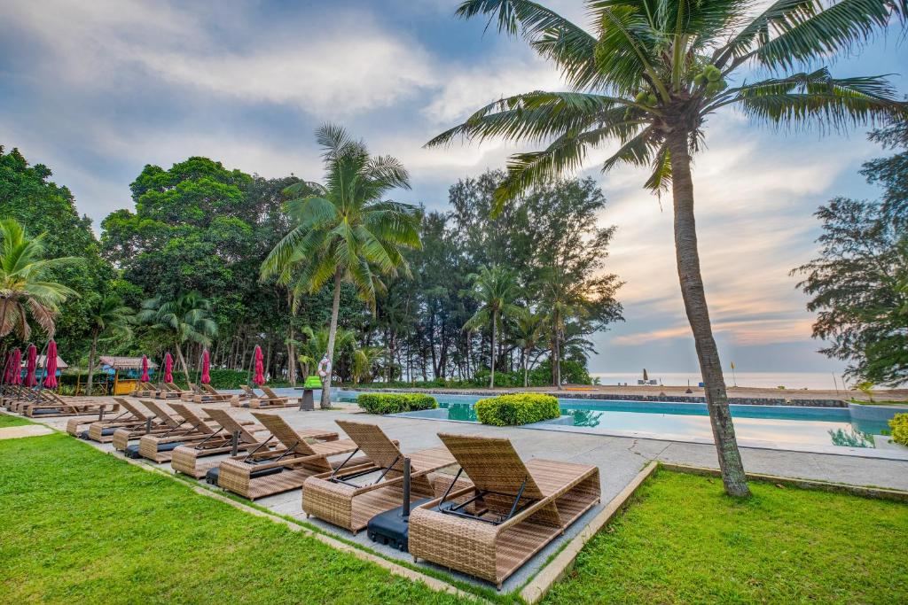 - une rangée de chaises longues à côté d'une piscine bordée de palmiers dans l'établissement Estella Phuket Mai Khao Beach Resort, à Mai Khao Beach