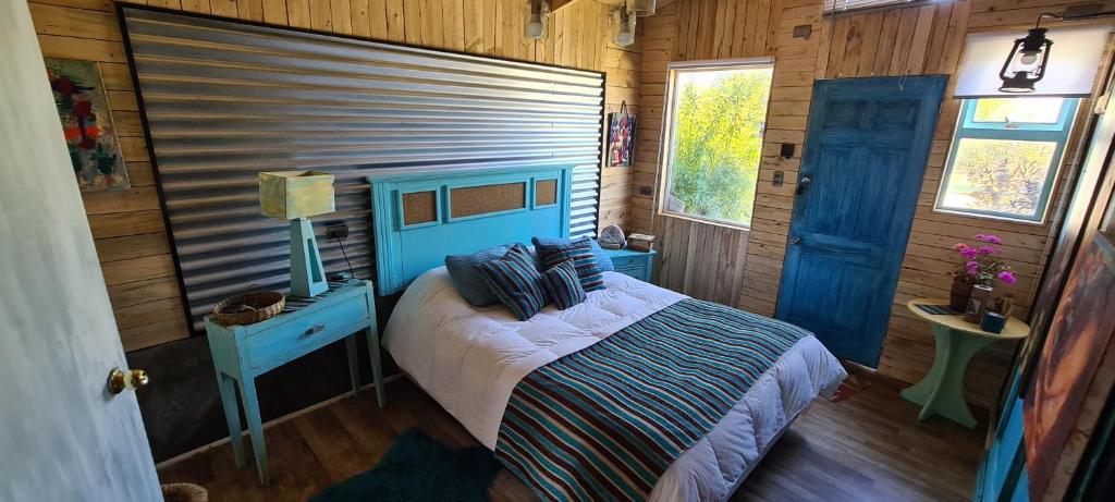 1 dormitorio con 1 cama en una cabaña de madera en Alojamiento Dominga, en Puerto Varas