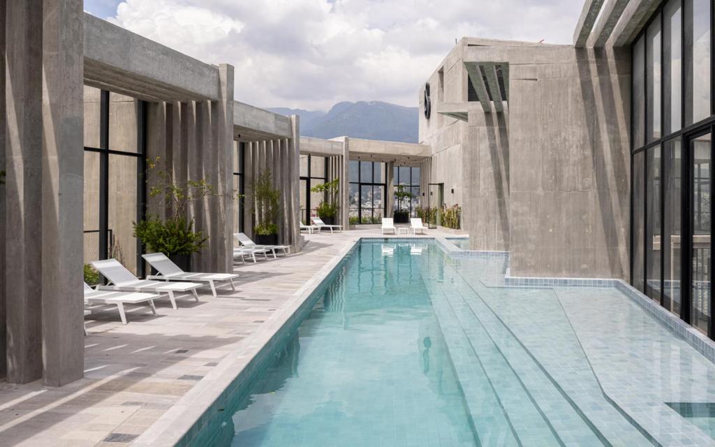 een groot zwembad met stoelen en een gebouw bij Nomad-In Luxury Suites and Apartments in Quito