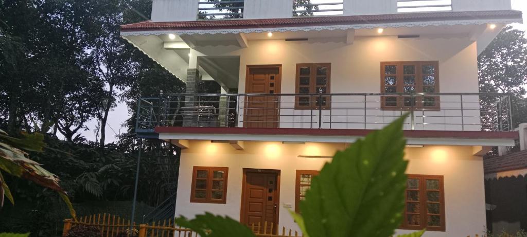 a white house with a balcony on top of it at Silver home stay vagamon in Vagamon