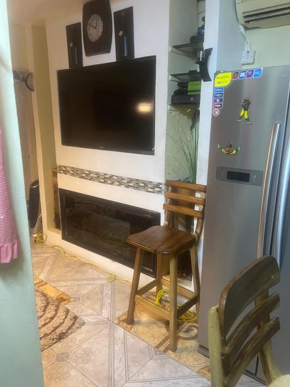 a kitchen with a tv and a chair and a refrigerator at Jamaican R Home in Kingston