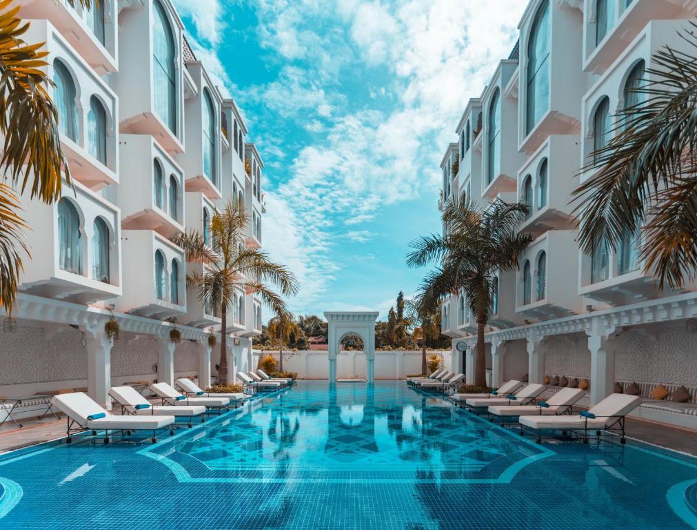 a swimming pool in the courtyard of a building with chairs and palm trees at The Wander by Sarai in Siem Reap