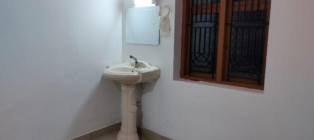 a white bathroom with a sink and a window at Vibgyor Home away from Home in Kānnangād