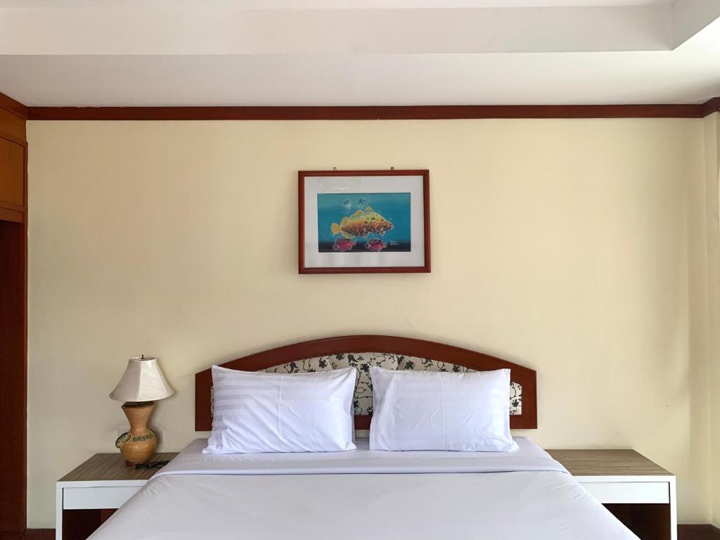 1 cama con almohadas blancas y una foto en la pared en Priew Wan Guesthouse, en Patong Beach