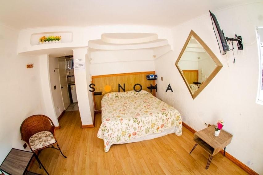 a bedroom with a bed and a mirror and a table at Apart Hotel Sonoma in Viña del Mar