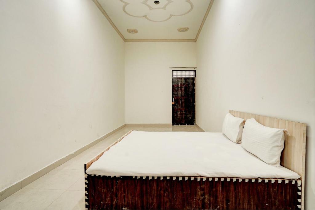 a small bedroom with a bed with white sheets at Spot On Chaudhary House in Hāthras