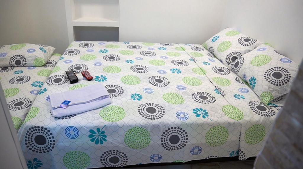 a bedroom with a bed with a white and green comforter at Apartaestudio Vista azul rodadero Mara 502 in Santa Marta