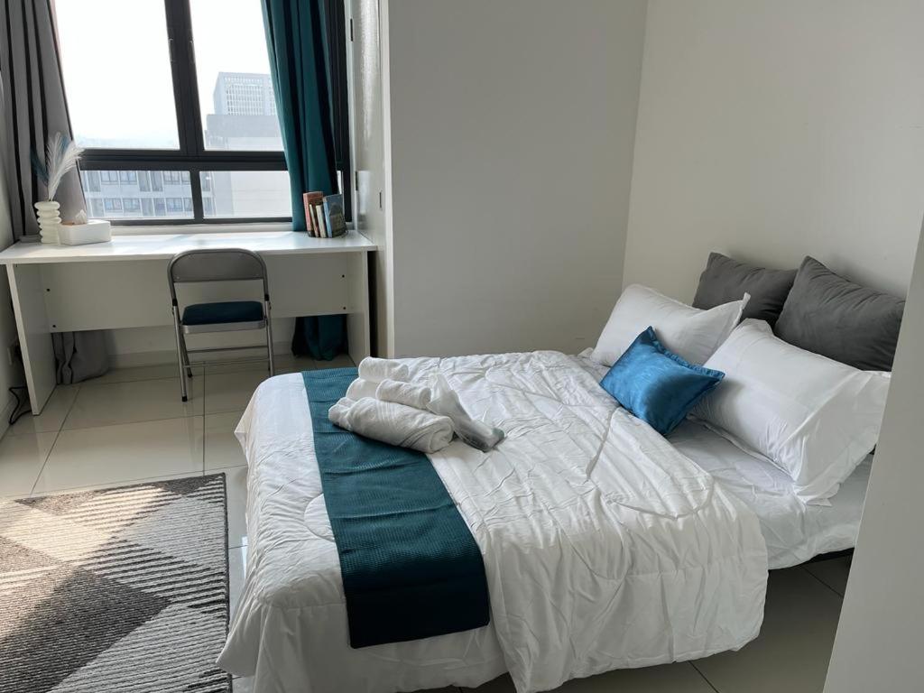 una camera da letto con letto con cuscini blu e scrivania di horizon suite 25-11 a Sepang