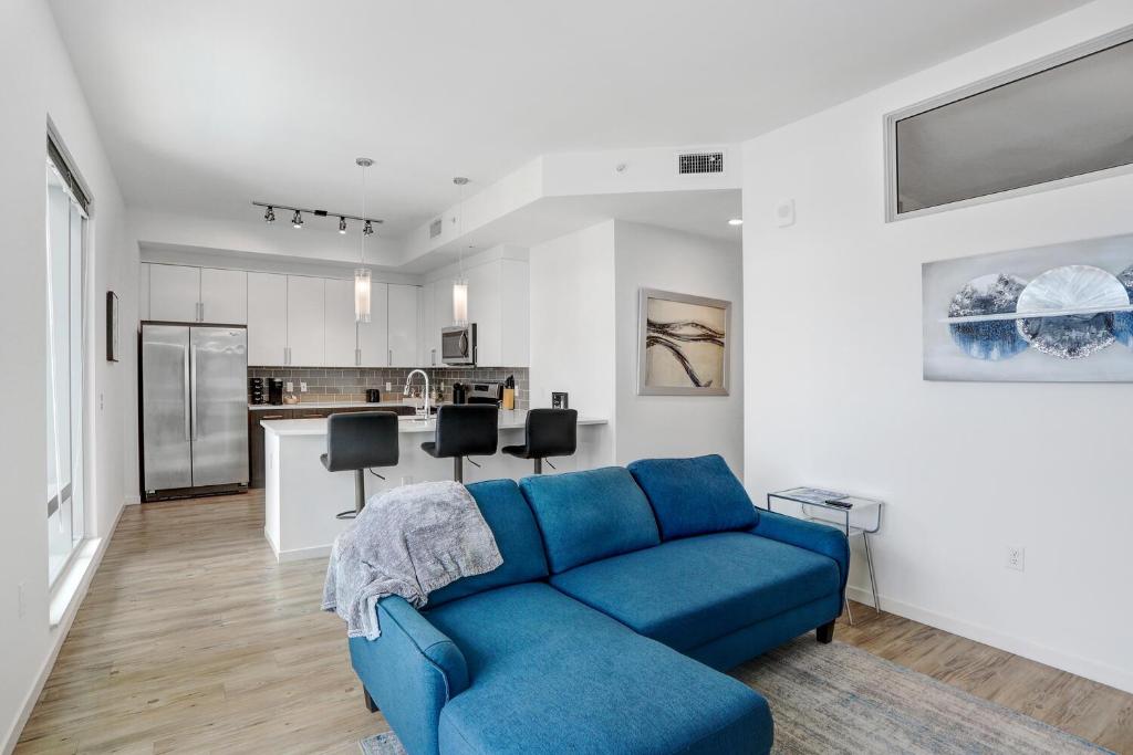 uma sala de estar com um sofá azul e uma cozinha em Sunset Views from a Stylish 1BR High Rise in Tampa em Tampa