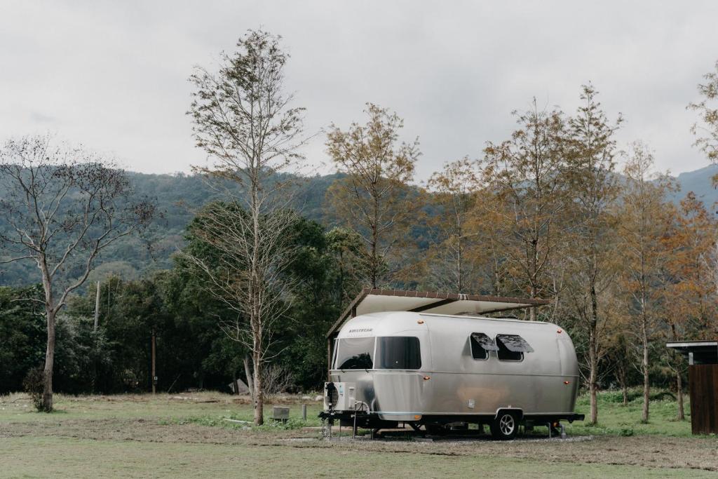 a white trailer parked in a field next to trees at The Silence Manor in Ruisui