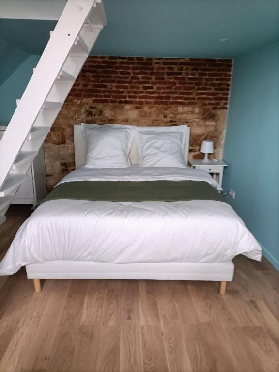 - une chambre avec un lit blanc et un mur en briques dans l'établissement LE PAPILLON BLEU, à Honfleur