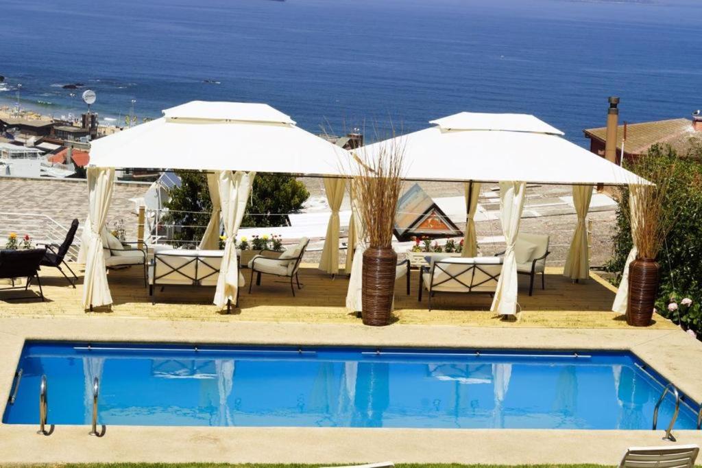 - une piscine avec 2 parasols, une table et des chaises dans l'établissement FINTUPS SPA, à Viña del Mar