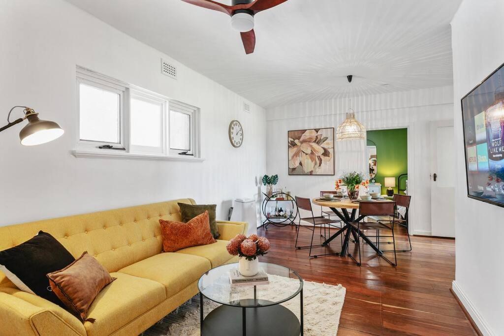 a living room with a yellow couch and a table at Vintage 2BR CBD Apartment w/River View in Perth