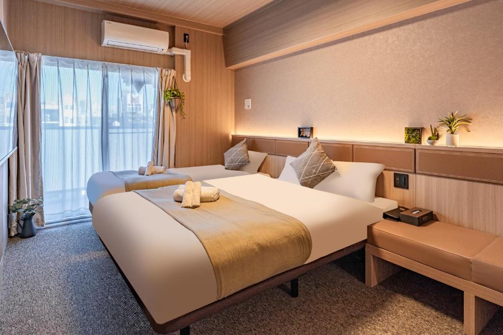 een hotelkamer met 2 bedden en een raam bij Apartment Hotel 11 Dotonbori II in Osaka