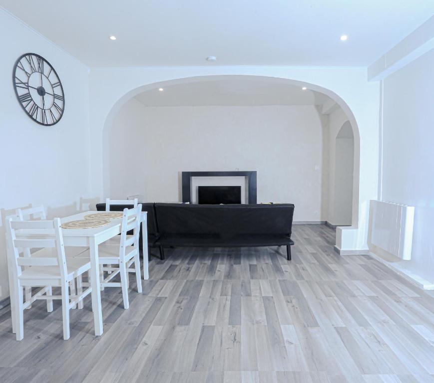 sala de estar con mesa, sillas y reloj en Élégant appartement bord de Seine, en Montereau-Fault-Yonne