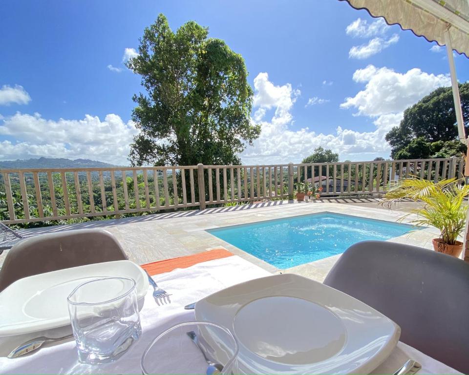 a table with chairs next to a swimming pool at Appartement T2 - vue campagne in Le Robert