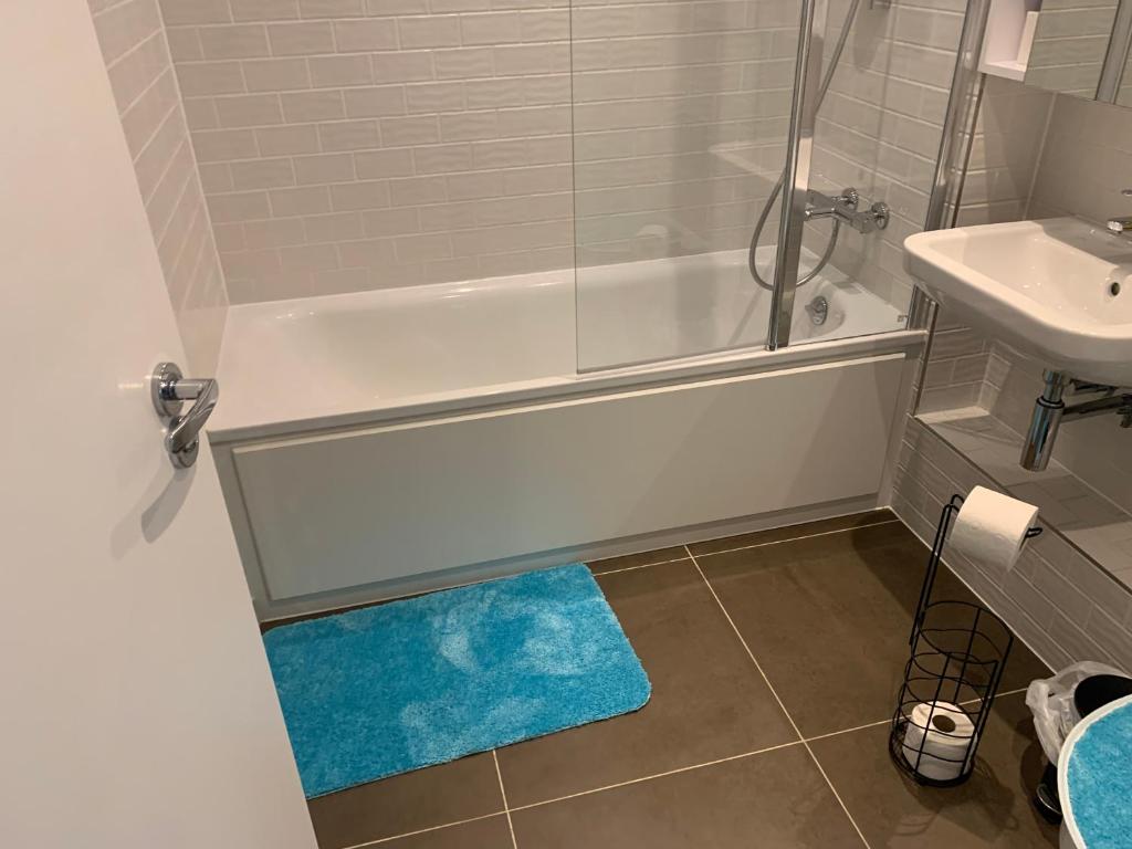 a bathroom with a tub and a sink and a blue rug at Luxe High rise Apartment with beautiful views & free parking in Woolwich