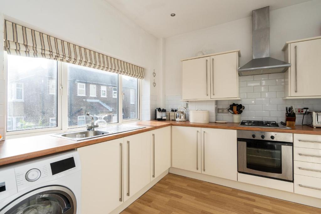 a kitchen with white cabinets and a sink and a window at Beautiful 2 Bedroom Flat on Street Lane in Moortown