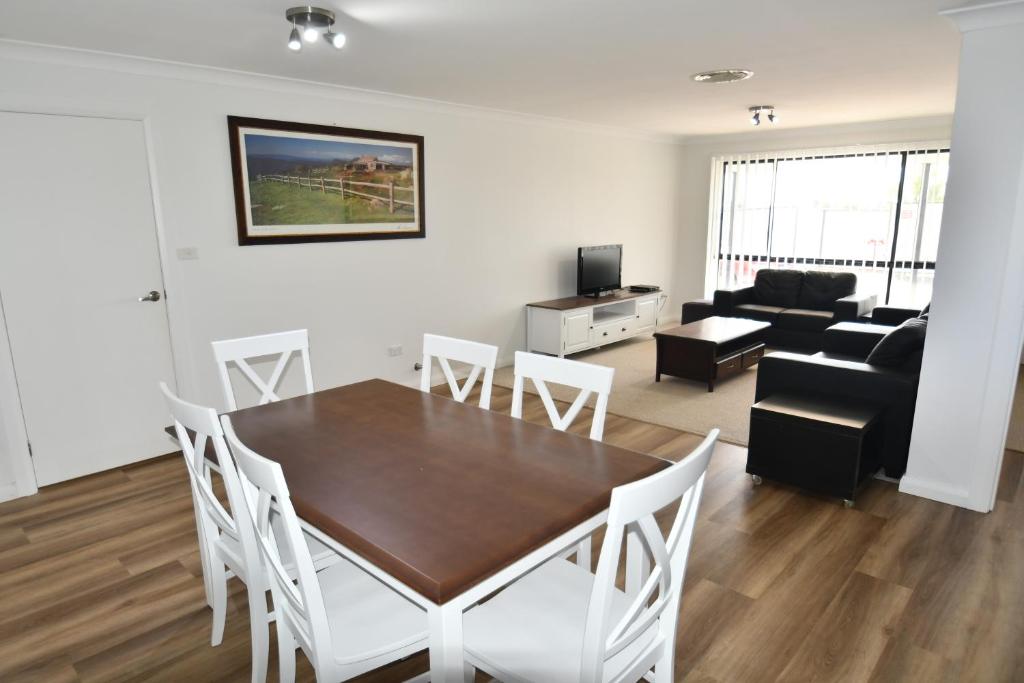 a dining room and living room with a table and chairs at Ascot Gardens Serviced Apartments in Dubbo