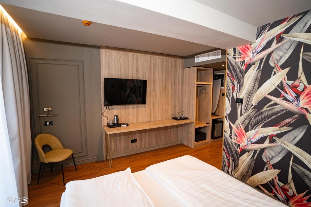 1 dormitorio con 1 cama y TV en la pared en Cosmopolita Boutique Hotel, en Timisoara