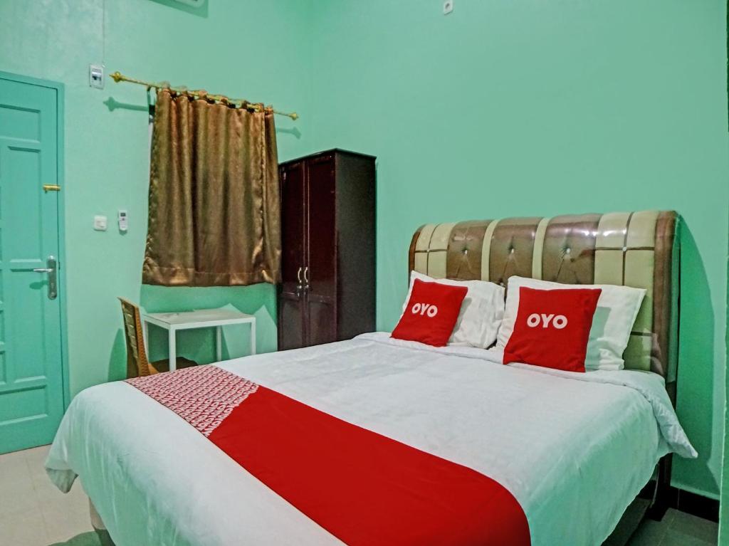 ein Schlafzimmer mit einem großen Bett mit zwei roten Kissen in der Unterkunft OYO 92950 Orien Guesthouse in Pematangsiantar