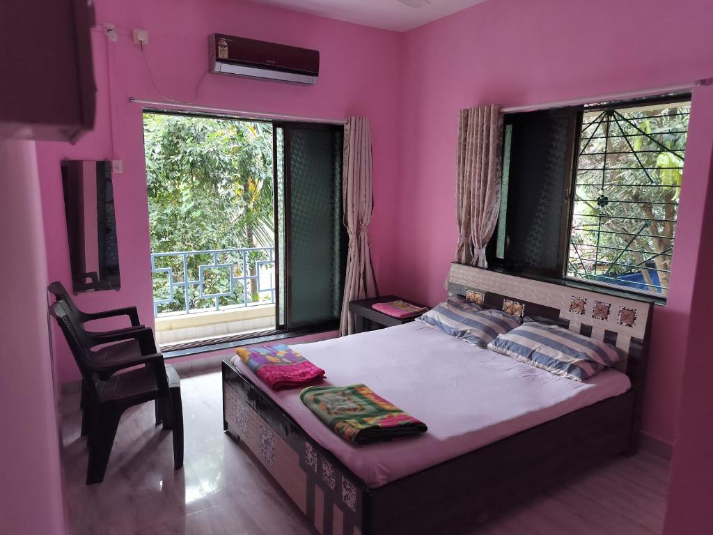 sypialnia z różowym pokojem z łóżkiem i krzesłem w obiekcie Gulmohar Cottages - Home Stay in Alibag w mieście Alibag