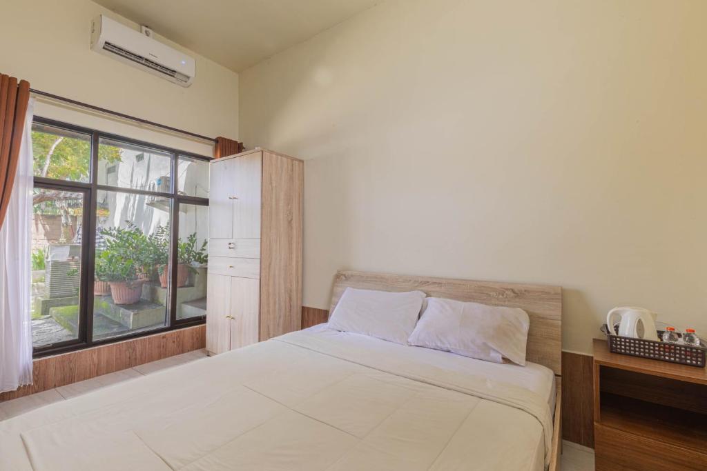 - une chambre avec un grand lit et une fenêtre dans l'établissement Penginapan Asri, à Mataram