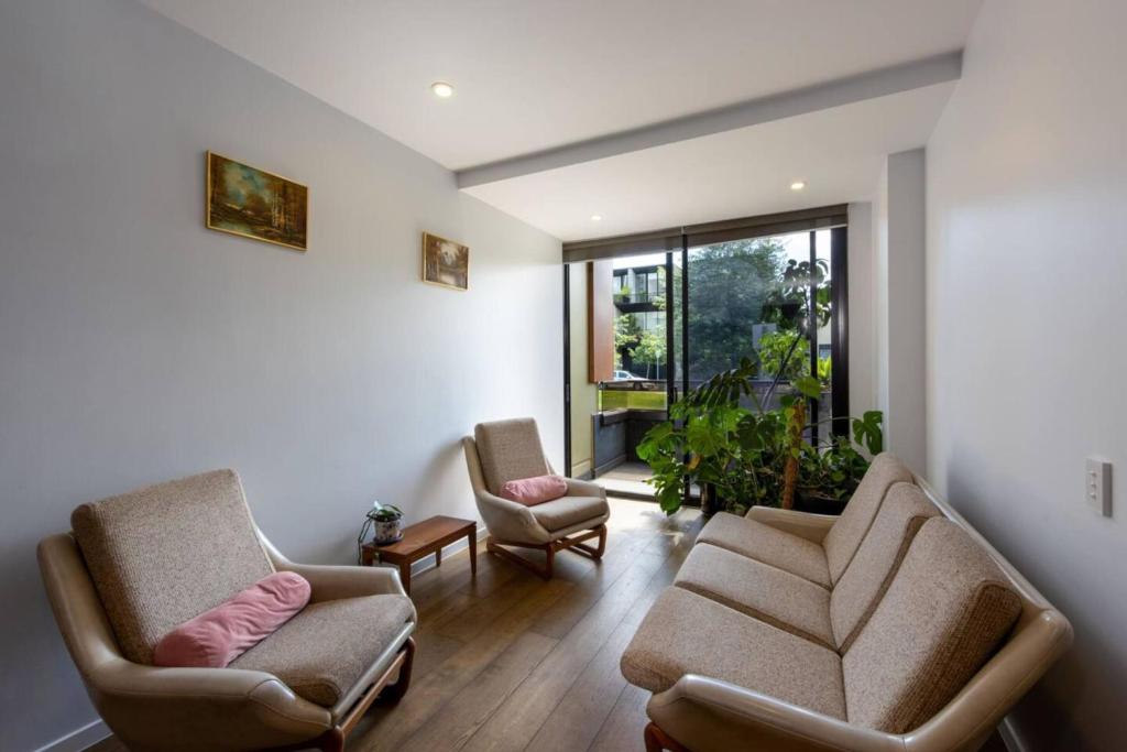 sala de estar con 2 sillas y sofá en Cozy 1Bed Unit in leafy Carlton - 10 mins from CBD, en Melbourne