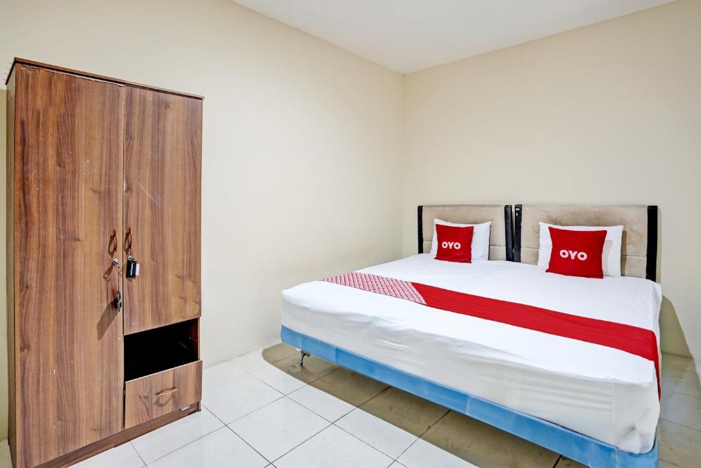um quarto com uma cama grande e almofadas vermelhas em OYO Life 93111 Garden Homestay 2 Merlion em Lontar