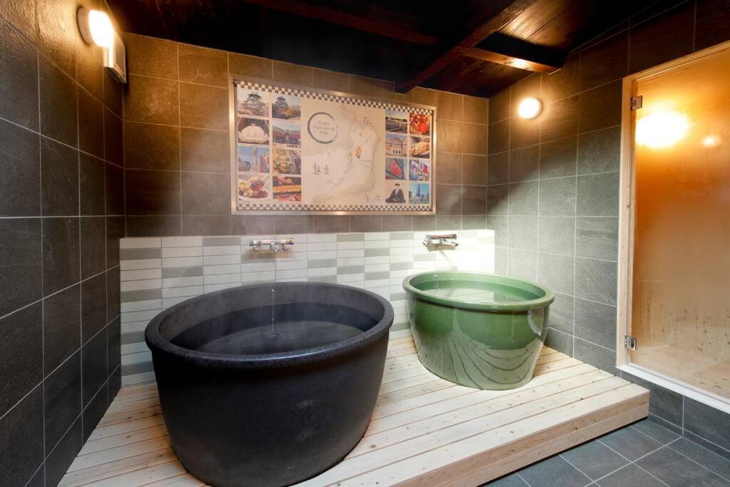 baño con bañera grande y cubo verde en かまどと壺湯之宿 大阪ミナミ–Residence inn Kamado and Tsuboyu-, en Osaka