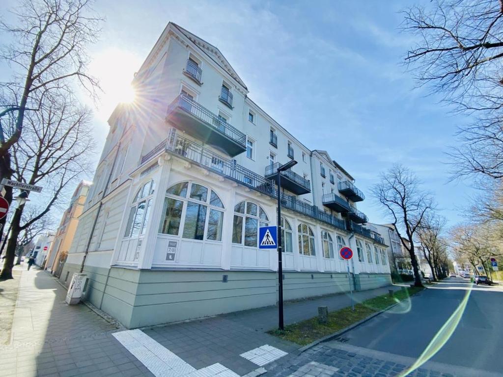a building on a street with the sun behind it at Traumstrand, am Kurpark in Warnemünde