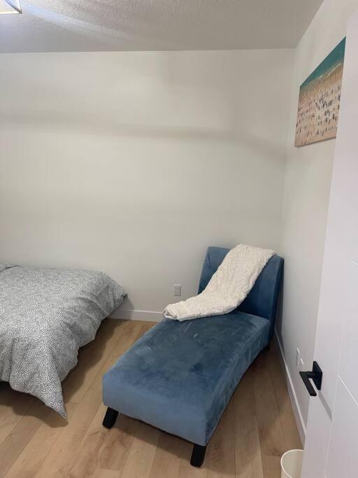 a bedroom with a bed and a blue couch at Stylish 2 Bedroom suite in SW Edmonton close to Windermere and Edmonton International Airport in Edmonton