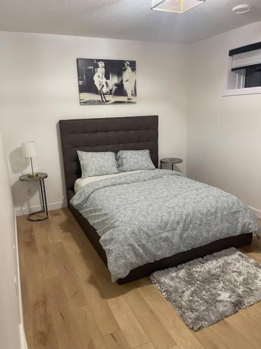 a bedroom with a bed with a gray comforter at Stylish 2 Bedroom suite in SW Edmonton close to Windermere and Edmonton International Airport in Edmonton