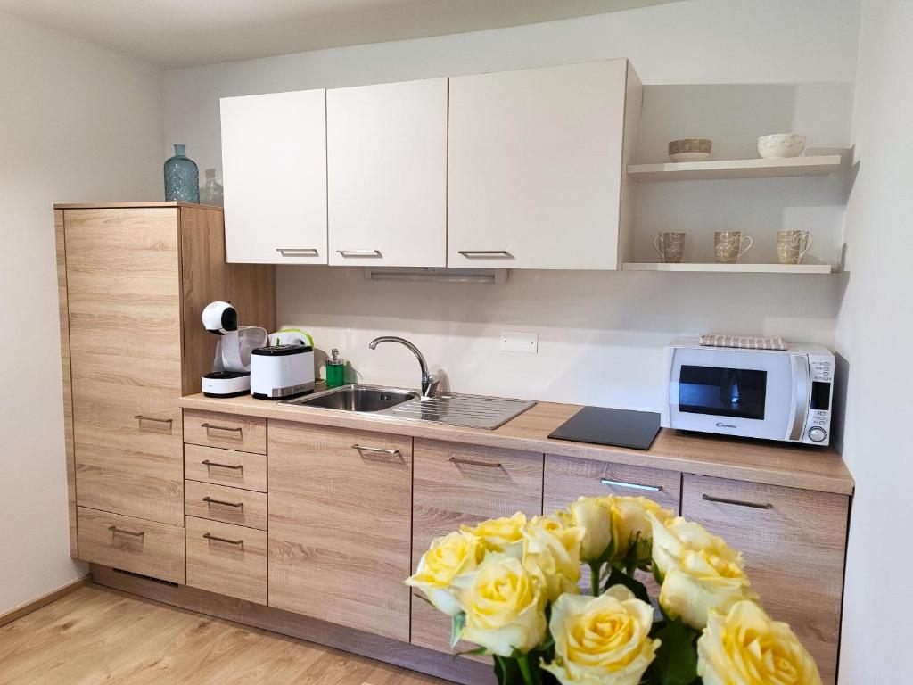 una cocina con armarios blancos y rosas amarillas en Sweet Stay Roznik Apartment, en Liubliana