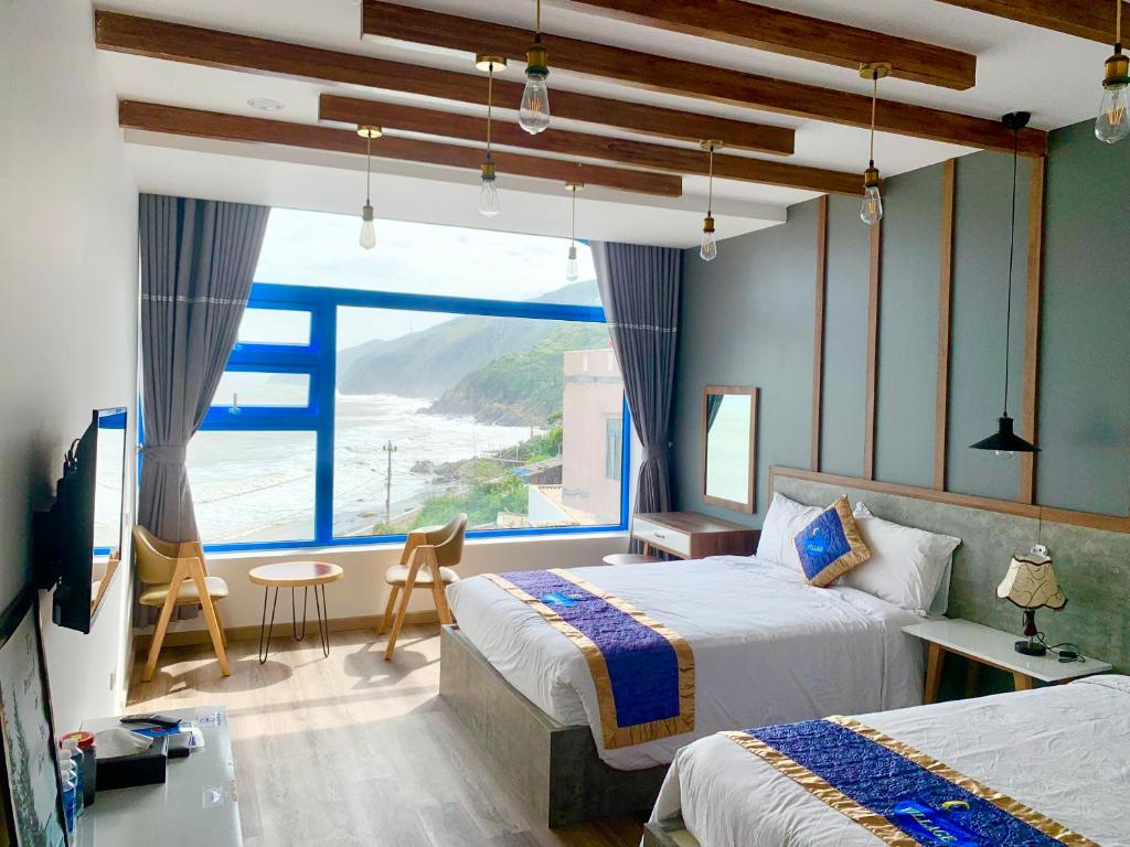 a bedroom with two beds and a large window at Chai Village Hotel in Quy Nhon