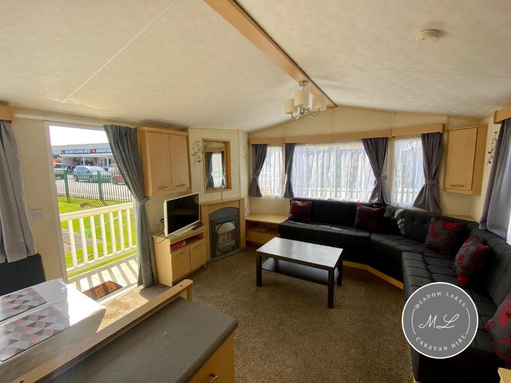 a caravan living room with a couch and a tv at Happy Days - Beachfields 370 in Chapel Saint Leonards