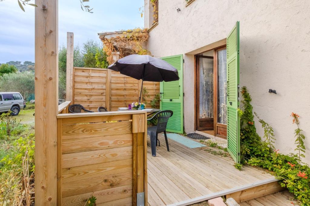 une terrasse en bois avec un parasol sur une maison dans l'établissement Appartement Vallon des prés, à Villeneuve-Loubet