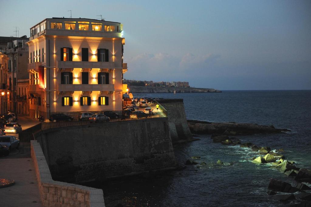 a building next to the ocean at night at Livingston Hotel in Siracusa