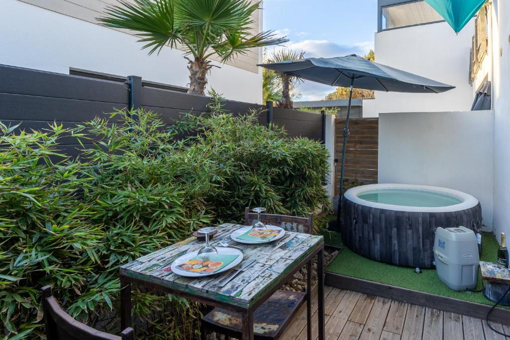 une table avec des assiettes de nourriture et un parapluie dans l'établissement Artemis, au Grau-dʼAgde
