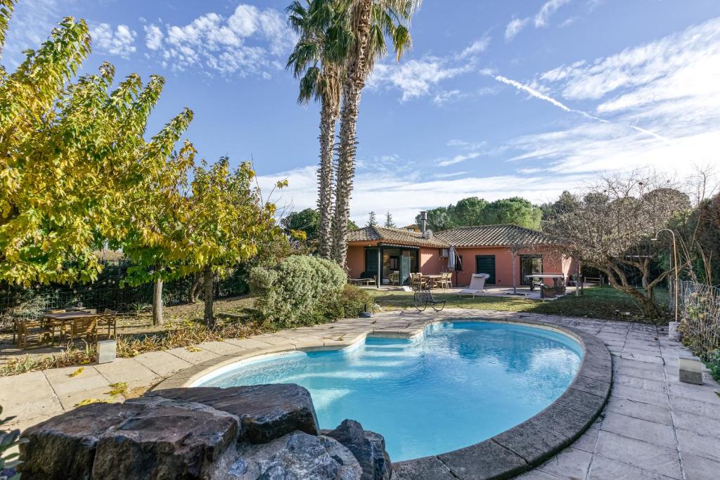 una piscina en un patio con una palmera en Villa Virginie Torremirona Resort, en Navata