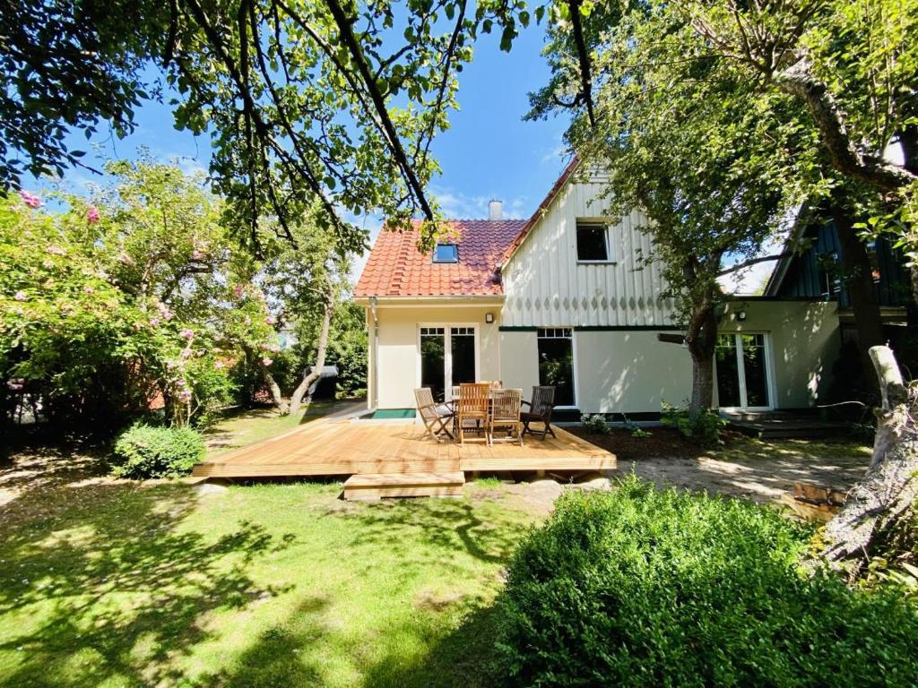 a backyard with a wooden deck and a white house at Sommerhaus am Bach in Warnemünde