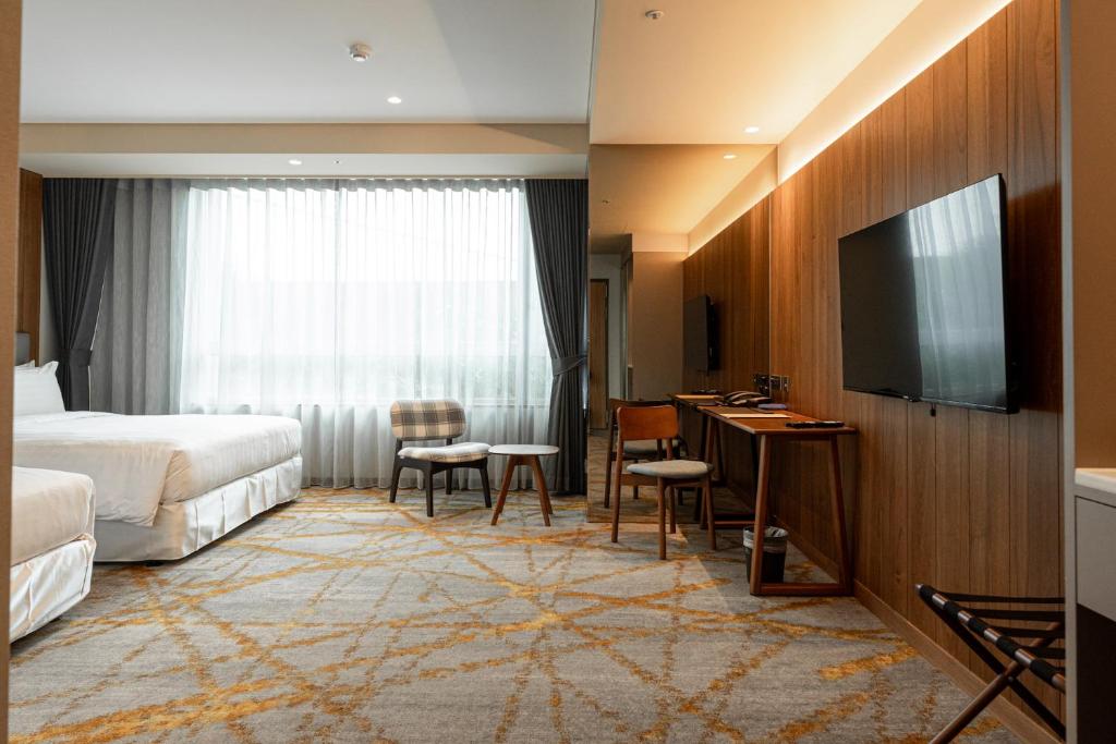 a hotel room with a bed and a flat screen tv at Home Hotel in Taipei